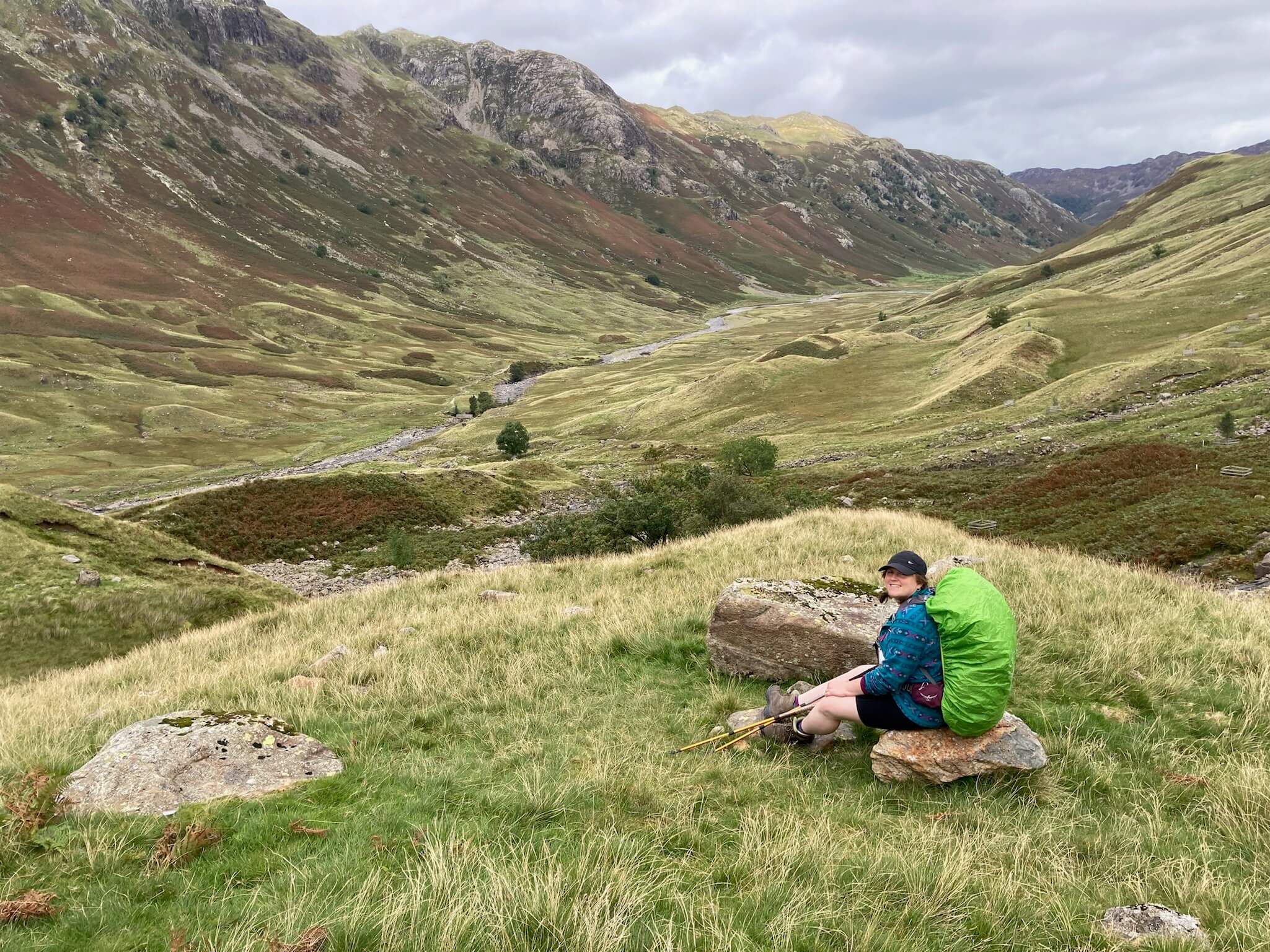 lydia resting on rock with view of borrowdale valley behind